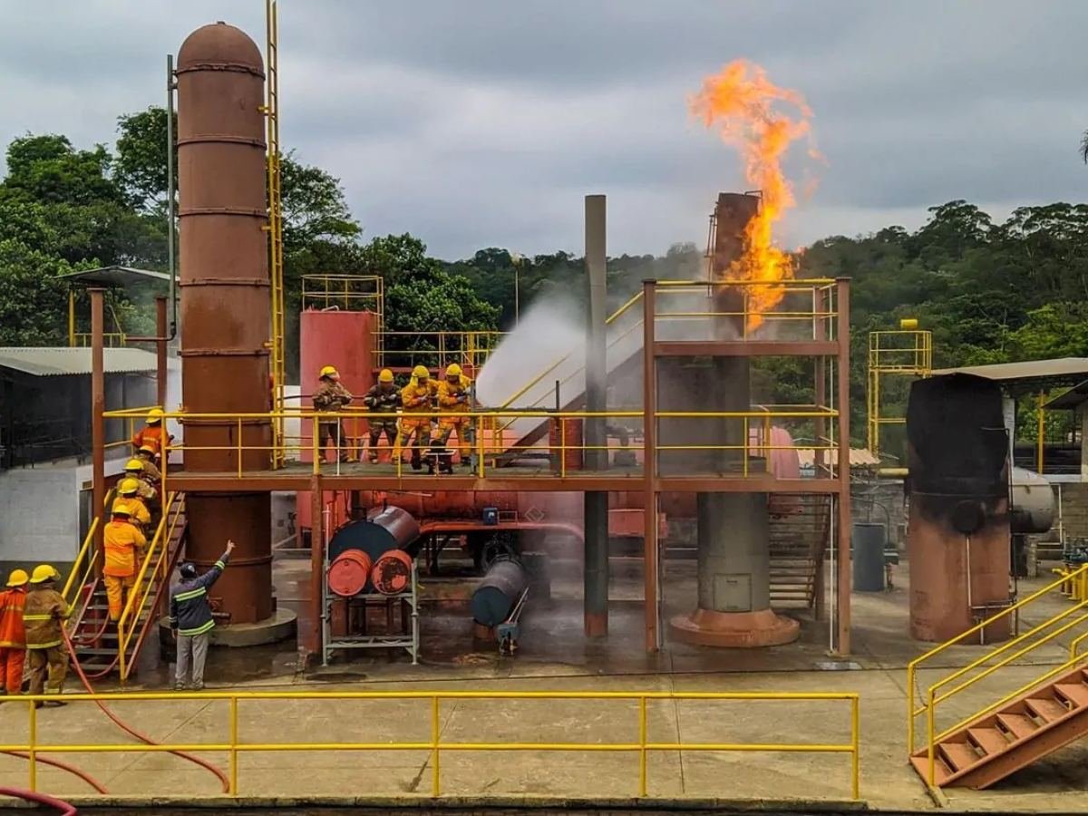 Simulador de planta industrial em chamas, com equipe aplicando água