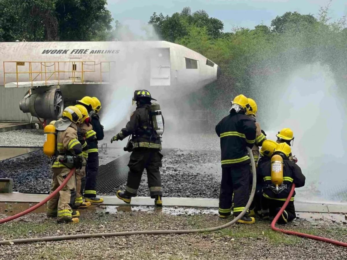 Bombeiros com equipamento de respiração junto ao mockup de aeronave