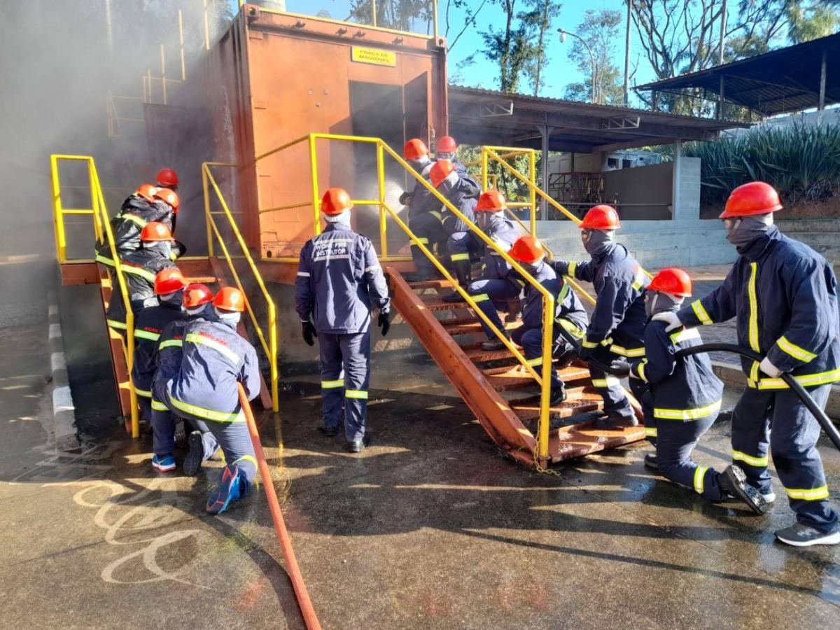 Brigadistas subindo a escada de um simulador com a mangueira