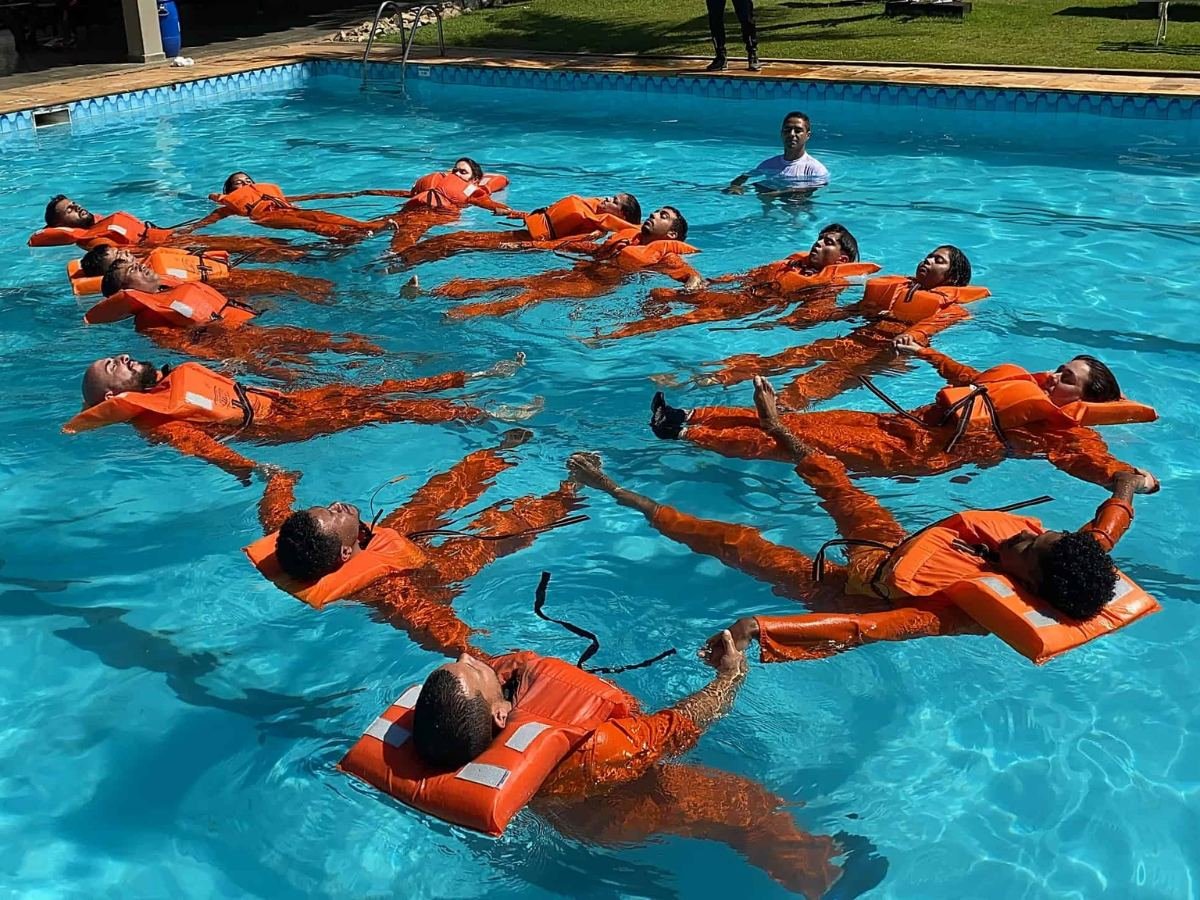 Alunos com roupas de sobrevivência flutuando em grupo na piscina